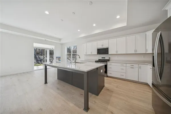 a kitchen with kitchen island a sink a stove a refrigerator and white cabinets
