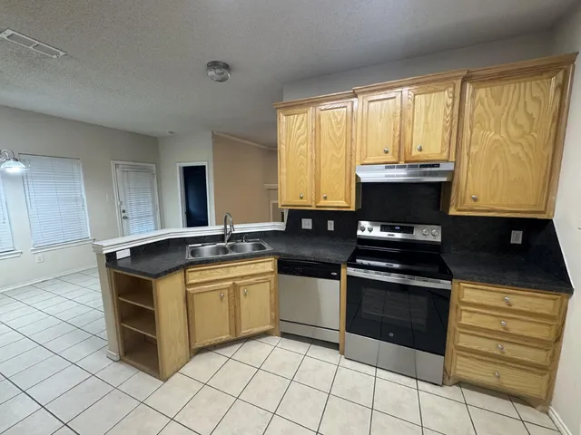 a kitchen with stainless steel appliances granite countertop a stove a sink and a microwave