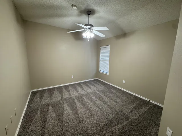 en empty room with ceiling fan and window