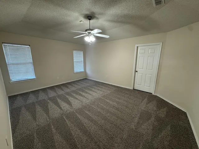 an empty room with a chandelier fan and windows