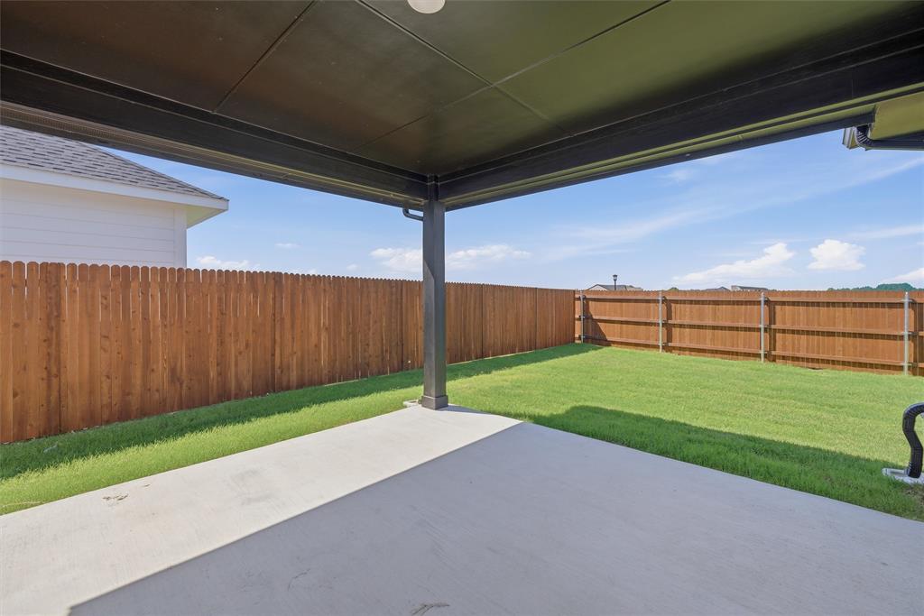 1213 Colca Drive Springtown, TX 76082 - Photo 18 of 23 Covered patio with concrete flooring, overlooking a grass lawn enclosed by a wood privacy fence