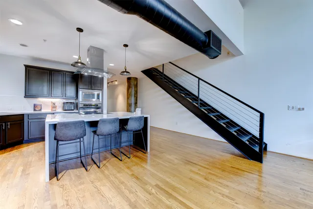 a living room with stainless steel appliances kitchen island lots of wooden furniture and a view of kitchen