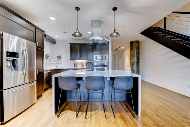 a kitchen with stainless steel appliances granite countertop a stove a refrigerator a kitchen island a sink and a refrigerator