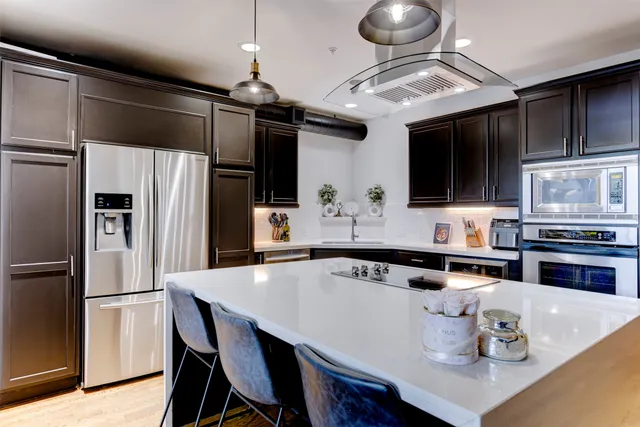 a kitchen with stainless steel appliances a dining table a stove a microwave and cabinets