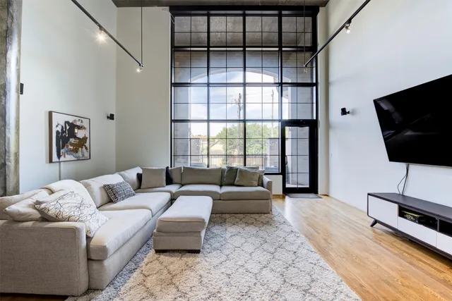 a living room with furniture a flat screen tv and a floor to ceiling window