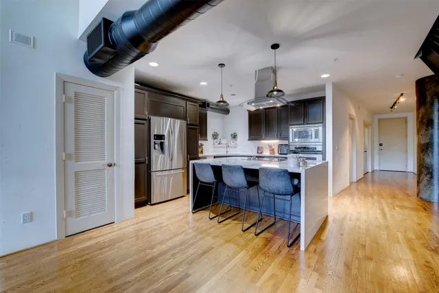 a kitchen with stainless steel appliances kitchen island a refrigerator and a wooden floor