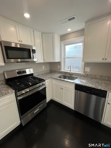 a kitchen with granite countertop a sink cabinets and stainless steel appliances