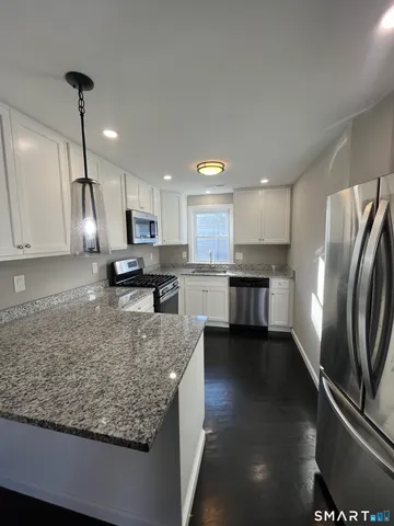 a kitchen with stainless steel appliances granite countertop a refrigerator sink and stove