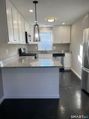 a large kitchen with stainless steel appliances a large counter top a stove a chimney a sink and a refrigerator