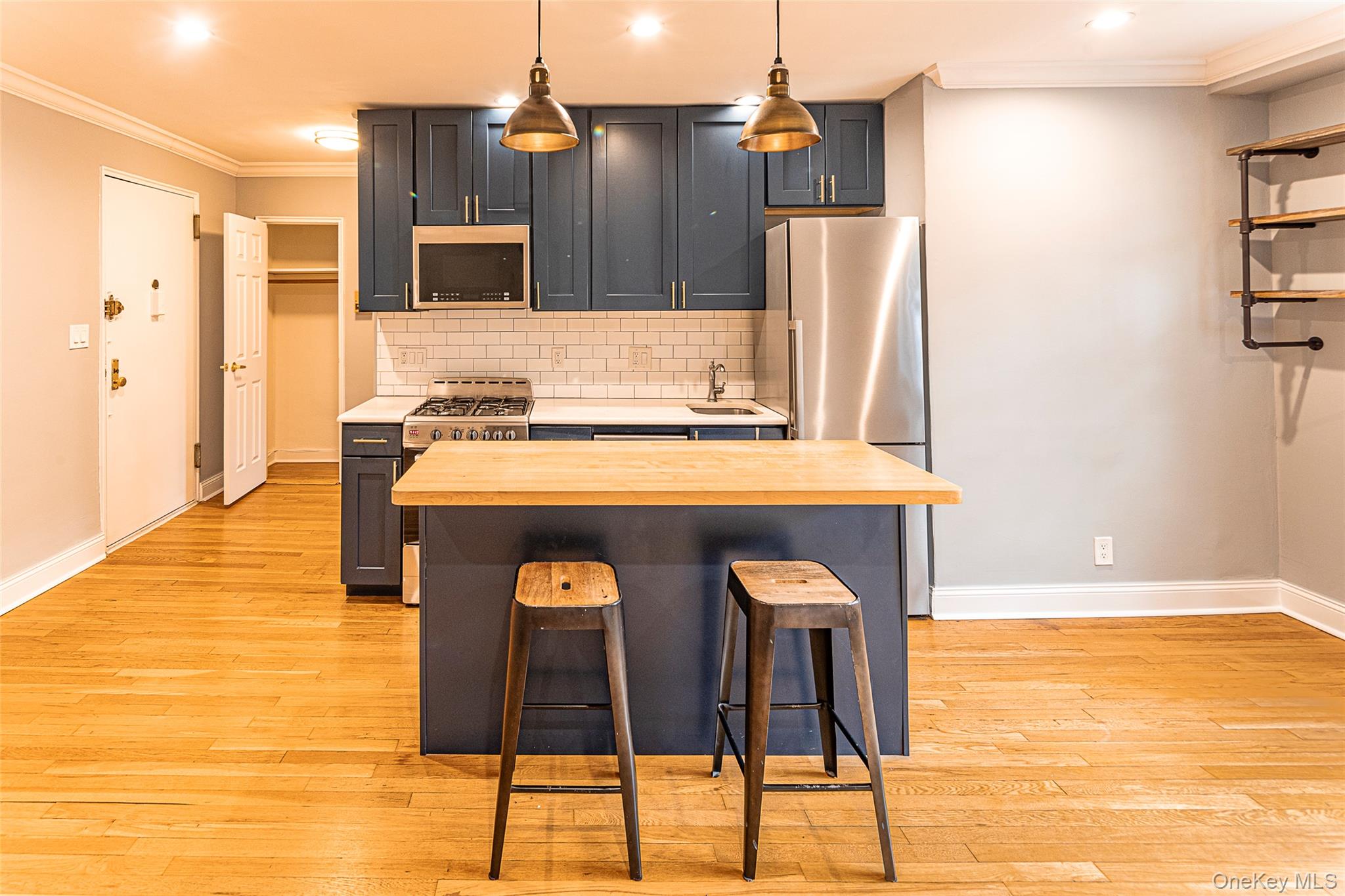 793 Palmer Road, Unit 3C Bronxville, NY 10708 - Photo 2 of 16 Kitchen with crown molding, a kitchen breakfast bar, butcher block island, stainless steel appliances, and decorative backsplash