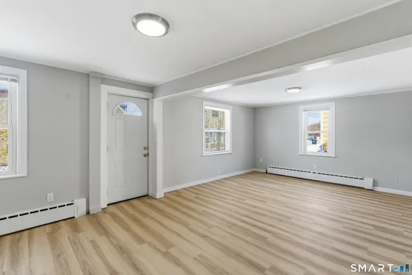 a view of an empty room with wooden floor and a window