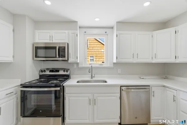 a kitchen with a refrigerator a stove top oven and wooden floor