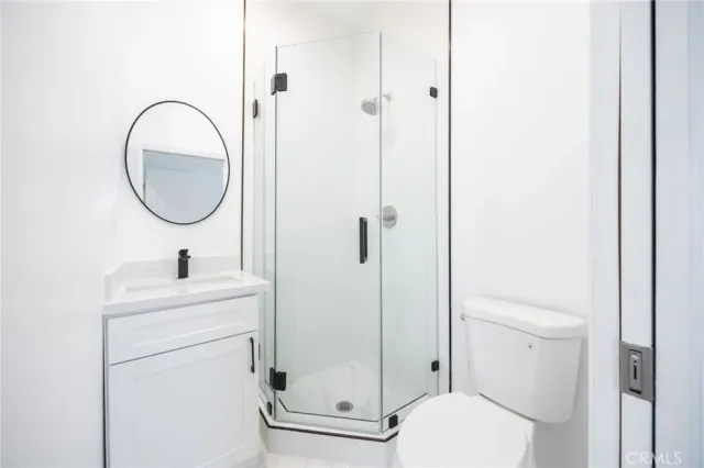 a bathroom with a toilet sink vanity and a shower