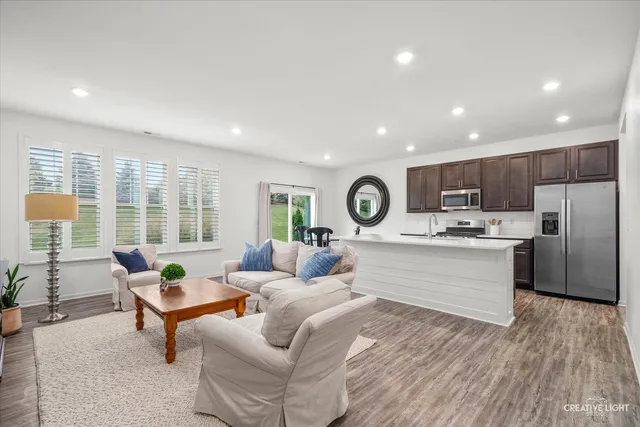 a living room with stainless steel appliances kitchen island granite countertop furniture a rug kitchen view and a window
