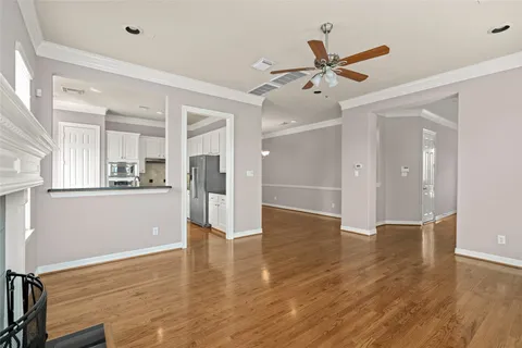 a view of an empty room with wooden floor and a ceiling fan