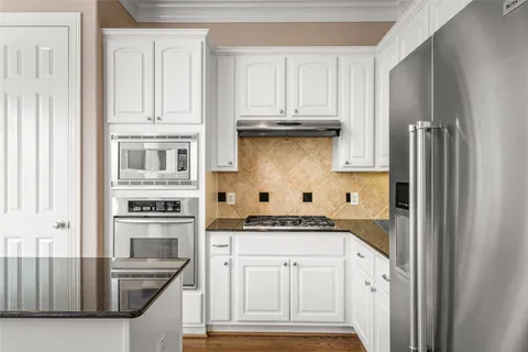 a kitchen with stainless steel appliances granite countertop a refrigerator and white cabinets