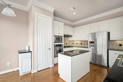 a kitchen with granite countertop white cabinets and stainless steel appliances