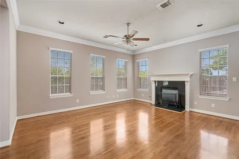 a view of an empty room with wooden floor fireplace and a window