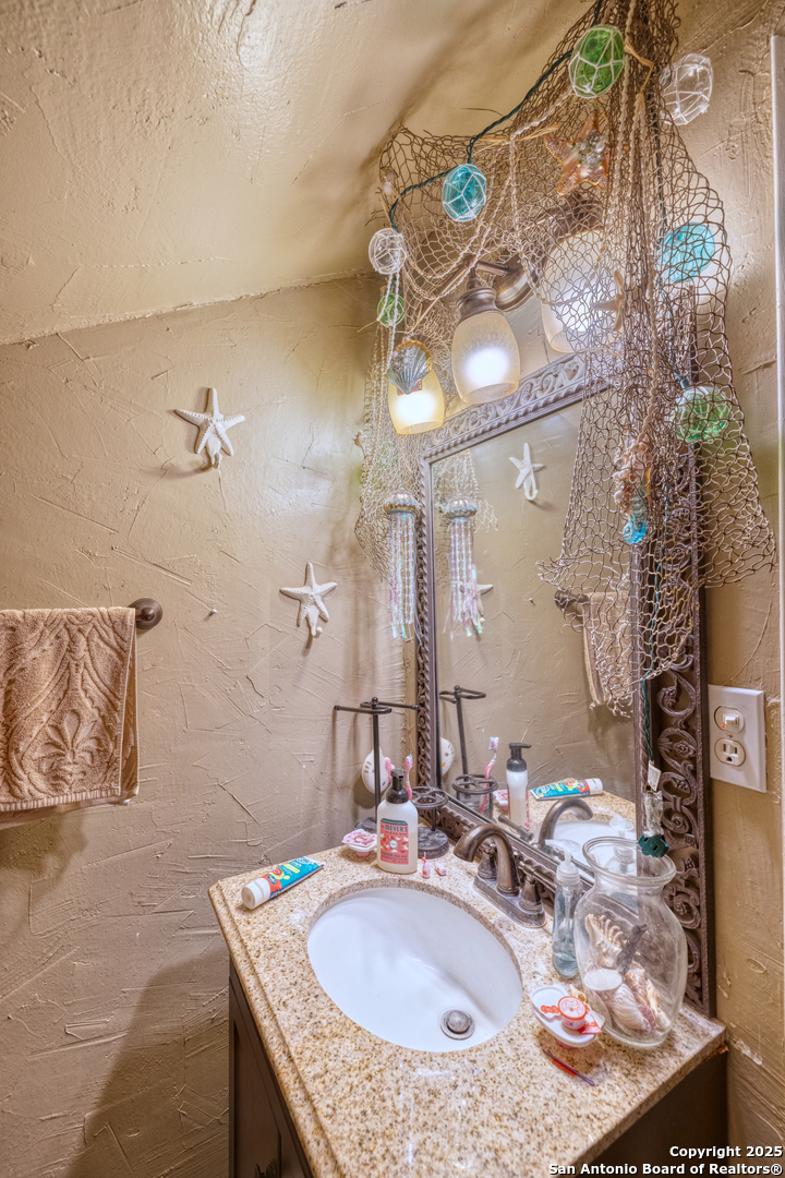518 North Getty Street Uvalde, TX 78801 - Photo 19 of 31 a bathroom with a granite countertop sink a mirror and shower