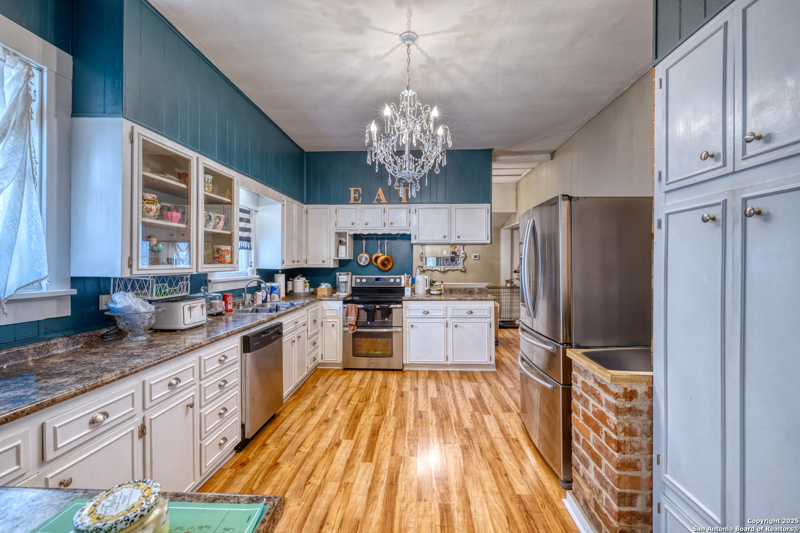 518 North Getty Street Uvalde, TX 78801 - Photo 4 of 31 a kitchen with granite countertop stainless steel appliances a refrigerator oven a sink dishwasher and white cabinets with wooden floor