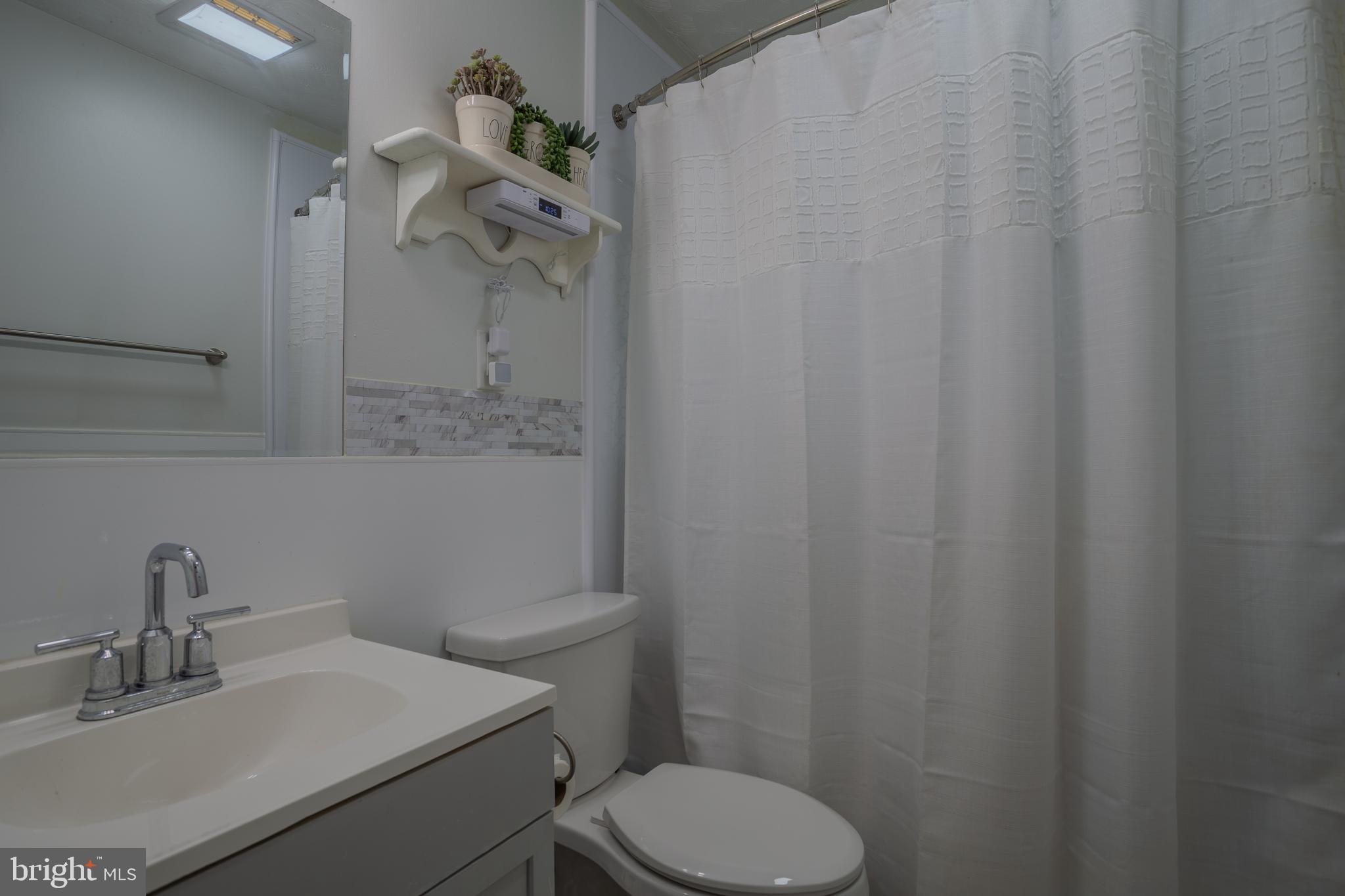 106 McDonald Street Ranson, WV 25438 - Photo 22 of 27 a bathroom with a sink a toilet and shower curtain
