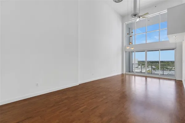 a view of an empty room with a window and wooden floor