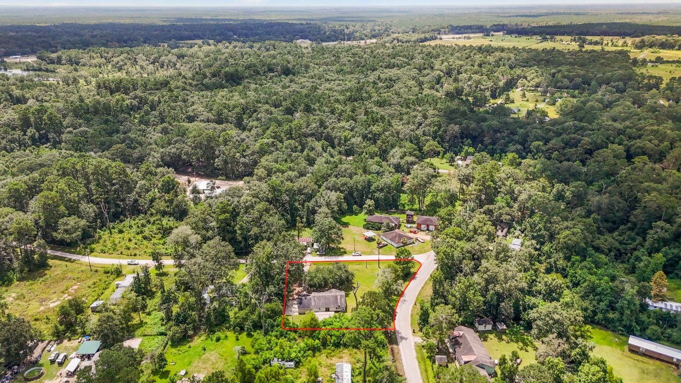 an aerial view of residential house with outdoor space and trees all around