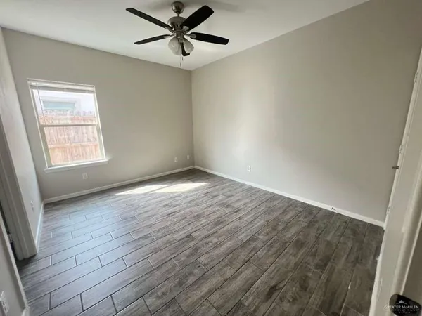 an empty room with wooden floor fan and windows