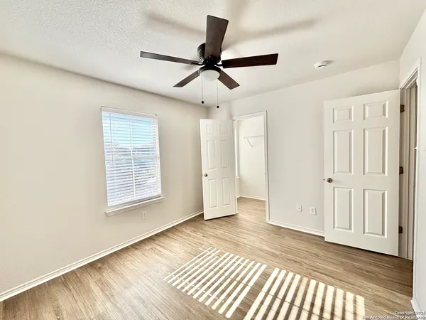 a view of an empty room with a window and wooden floor