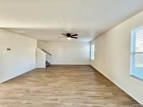 an empty room with windows and ceiling fan