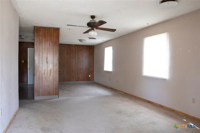 an empty room with windows and fan