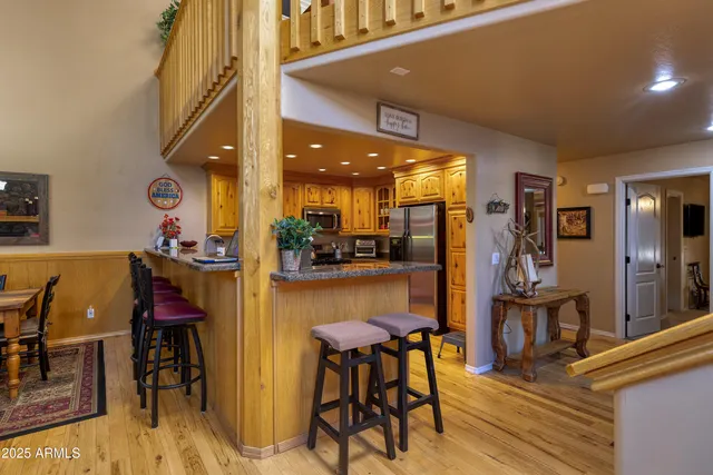 a kitchen with stainless steel appliances granite countertop a dining table chairs and a refrigerator