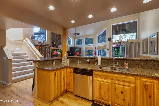 a kitchen with stainless steel appliances granite countertop a refrigerator a stove and a sink with wooden floor