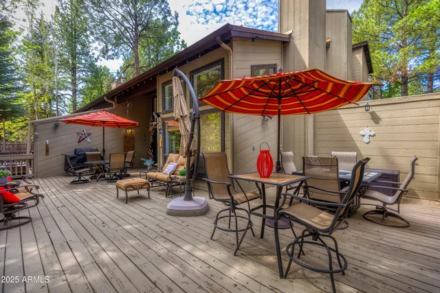 a view of a patio with table and chairs under an umbrella with wooden floor and fence