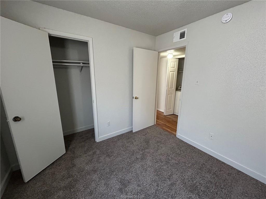 1535 Pine Ridge Drive, Unit C College Station, TX 77840 - Photo 11 of 14 Unfurnished bedroom with dark colored carpet, a textured ceiling, and a closet