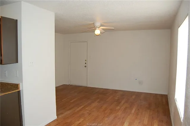 an empty room with wooden floor and fan