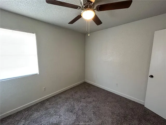 a view of an empty room and chandelier fan
