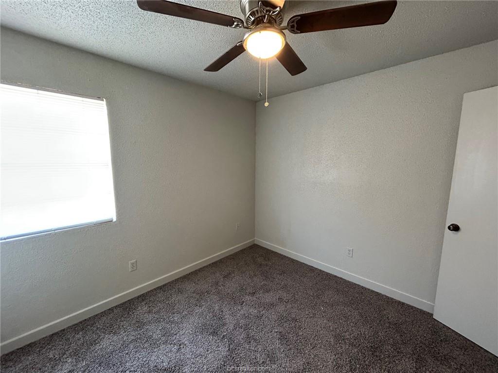 1535 Pine Ridge Drive, Unit C College Station, TX 77840 - Photo 6 of 14 Unfurnished room with dark colored carpet, a textured ceiling, and a textured wall