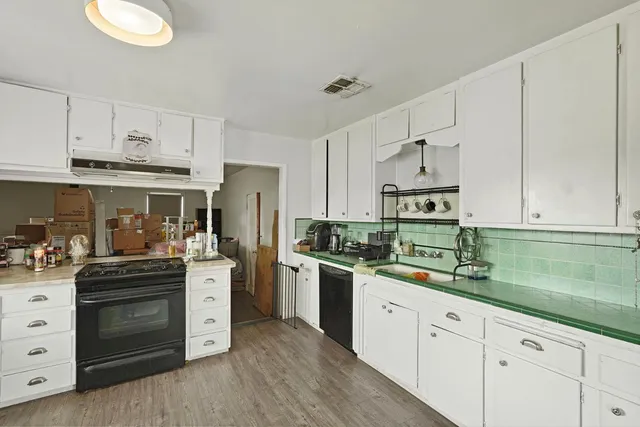 a kitchen with stainless steel appliances granite countertop a stove a sink and white cabinets