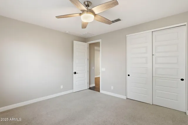 an empty room with closet and a ceiling fan