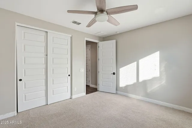 an empty room with windows and fan