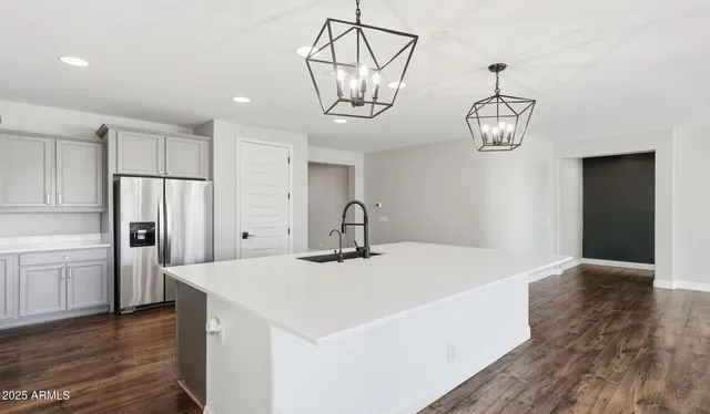 a kitchen with stainless steel appliances a white refrigerator a sink dishwasher with a dining table and chairs