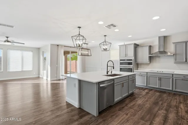 a kitchen with stainless steel appliances granite countertop a sink a stove and a wooden floors