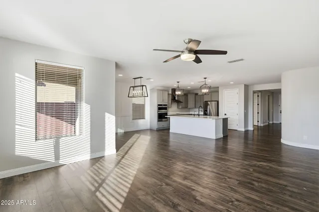 a view of a kitchen and an empty room with wooden floor and a kitchen