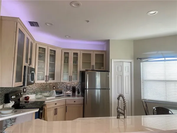 a kitchen with stainless steel appliances kitchen island granite countertop a refrigerator a sink dishwasher with a dining table and chairs