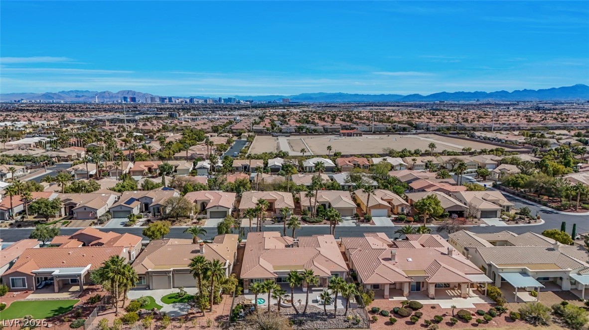 5015 Rivedro Street Las Vegas, NV 89135 - Photo 82 of 91 An aerial panorama reveals a vast residential community nestled against a distant metropolitan skyline and mountain ranges.