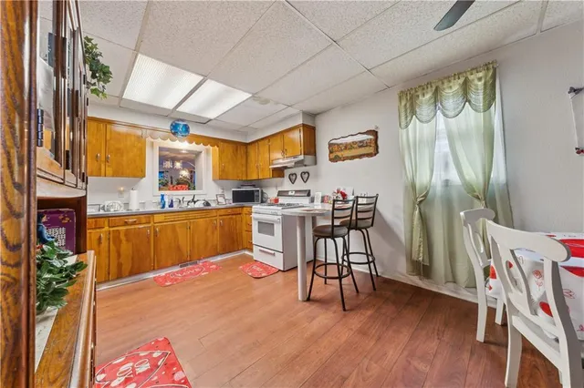 a room with stainless steel appliances kitchen island granite countertop a stove a sink dishwasher and a dining table with wooden floor