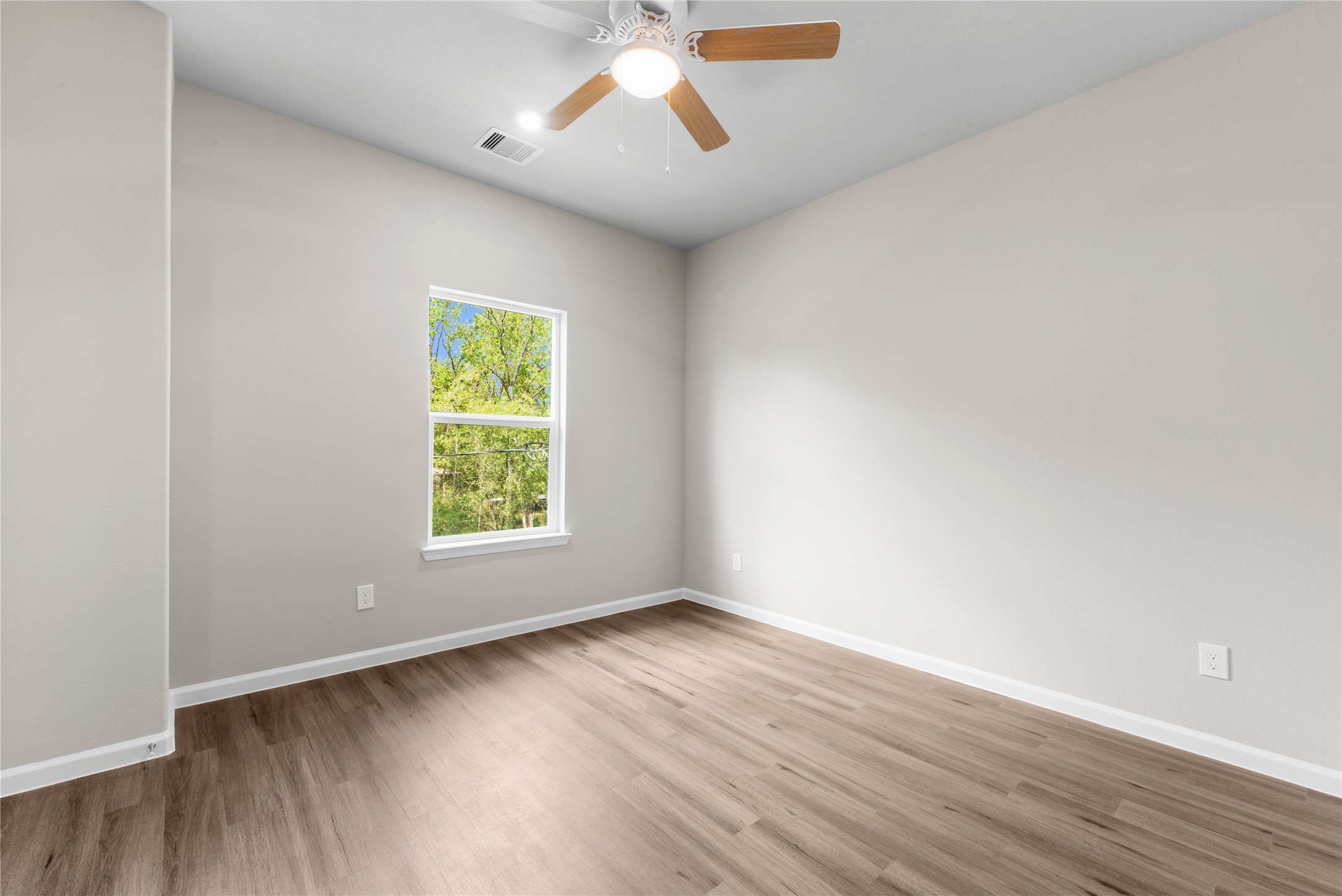 8161 Tate Street, Unit B Houston, TX 77028 - Photo 12 of 14 an empty room with wooden floor chandelier fan and windows