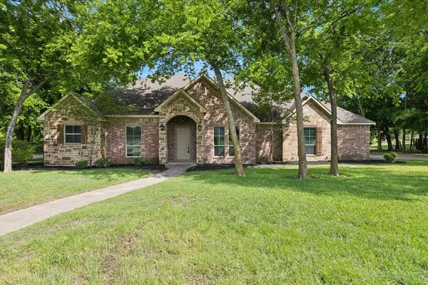 a front view of a house with a garden and trees