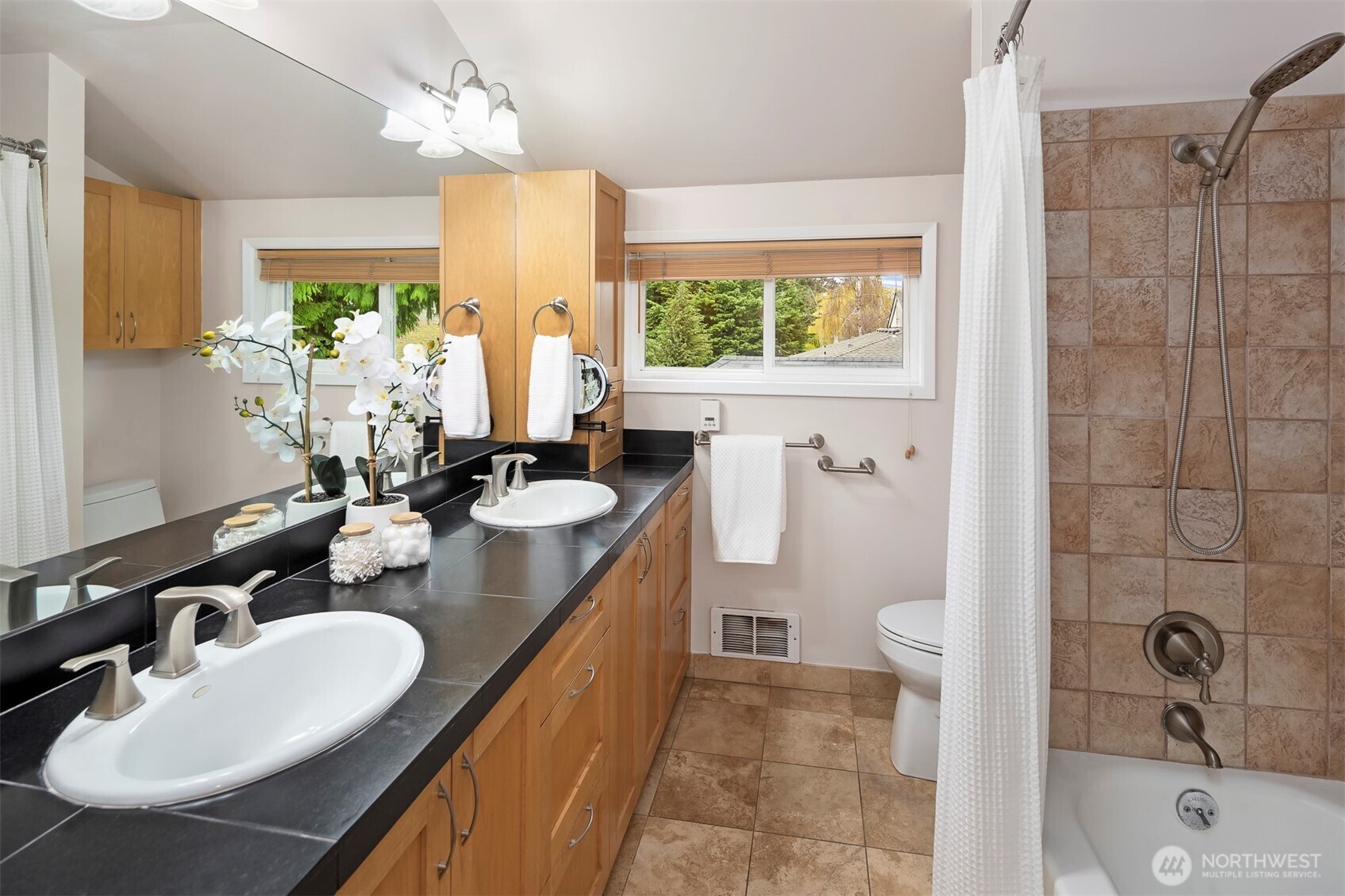 6939 Fauntleroy Way Southwest Seattle, WA 98136 - Photo 24 of 35 a bathroom with a double vanity sink a mirror a bathtub and next to a window